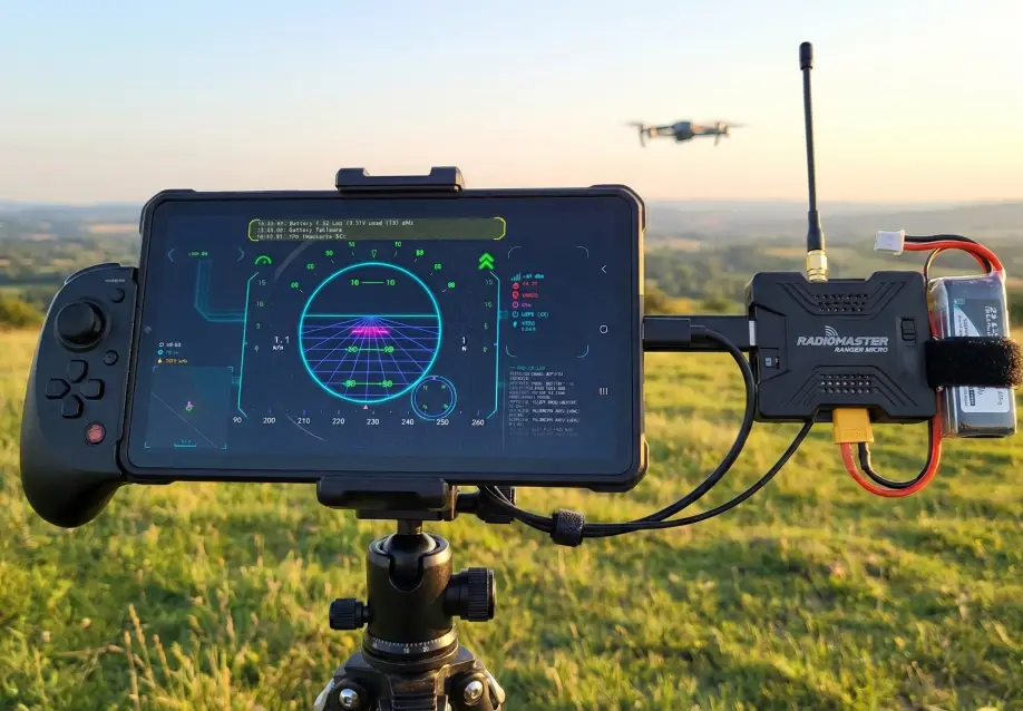 A Headless Transmitter setup featuring a RadioMaster ELRS module and Android phone on a gamepad, with a drone flying in the background